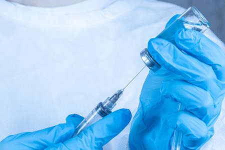 covid-19 sars-cov-2 vaccination: a health worker with a vaccine and a syringe in his handsの写真素材