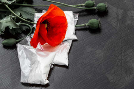 flowers and heads of opium poppy next to packages of heroin, soft focus, tinting, selective bleaching, enhanced contrastの写真素材