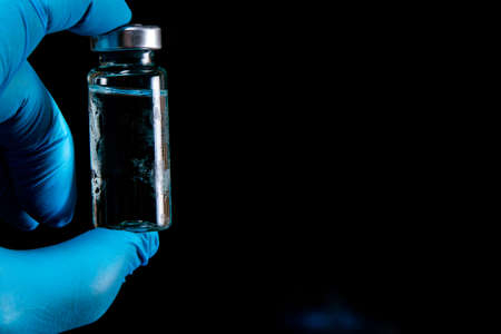 vaccine in a transparent glass ampoule, covered with frost, on a dark background, short focus, toningの写真素材
