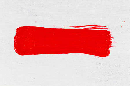 thick red acrylic paint applied in a thin, uneven stroke on a flat surfaceの写真素材