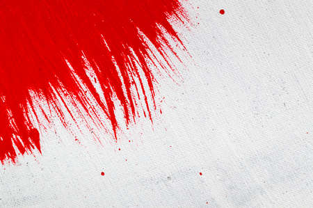 thick red bright acrylic paint applied unevenly on a light surfaceの写真素材