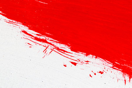 thick red bright acrylic paint applied unevenly on a light surfaceの写真素材