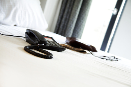 Telephone on bed in hotel roomの写真素材