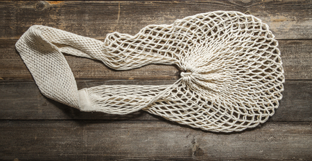 Mesh grocery bag isolated on wooden background