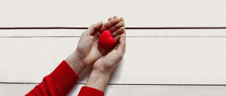 Valentine's day concept.Woman hands red heart on white tableの写真素材