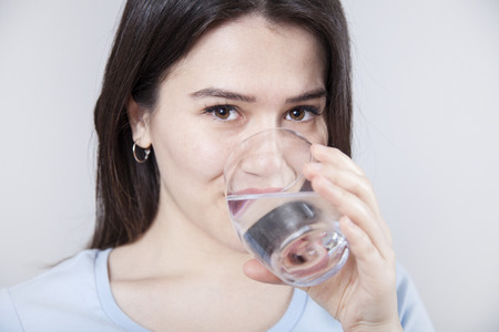 Portrait woman is drinking water on gray background