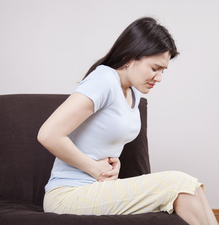 Young woman with stomach painの写真素材