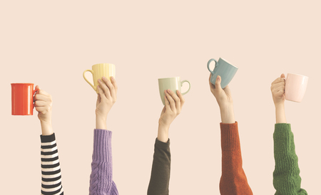 Many different arms raised up holding coffee cupの写真素材