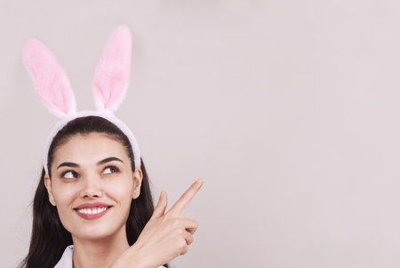 Festive bunny and eggs season. happy modern woman in Easter bunny ears isolated on pink backgroundの写真素材