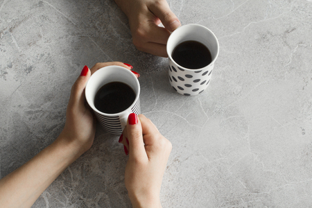 Person hands drinking coffee cup on gray backgroundの写真素材