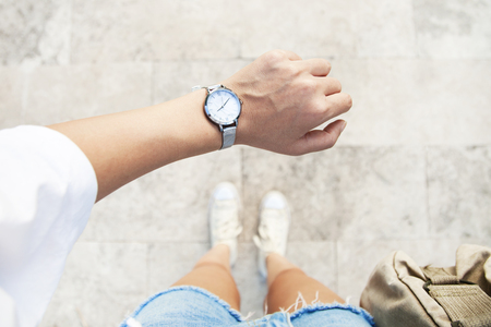 A young woman is late on time, in a hurry she checks the deadline on her classic watchの写真素材