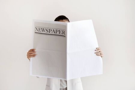 Woman reading newspaper on white backgroundの写真素材