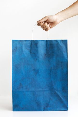 Person hand empty blank craft paper bag isolated on white background. Packaging template mock up.の写真素材