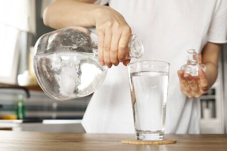 Young woman holds a glass of water. clean drinking water in a clear glass in your hands close-up.の写真素材