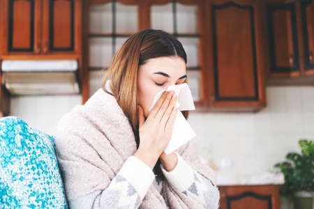 Sick young woman wipes her nose with a handkerchiefの写真素材