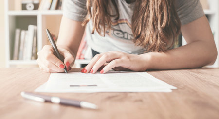Woman at office desk signing a contract with shallow focus on signature.の写真素材