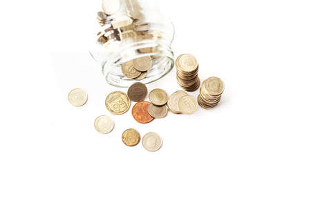 Overturned glass jar full of shined Golden coins on the white backgroundの写真素材