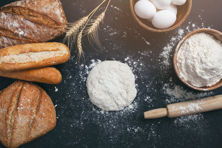 Bakery - gold rustic loaves of bread and flour on black chalkboard background.の写真素材