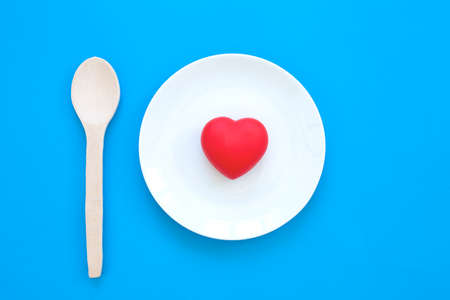 Plate with red heart and spoon on blue backgroundの写真素材