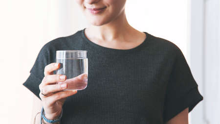 Woman drinking a fresh glass of water at home