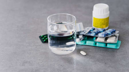 White medical pills and a glass of water on table, copy the space. The concept of medicine and...