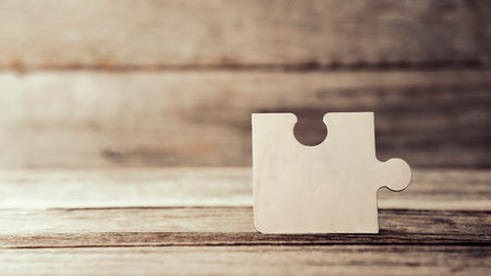 Brown pieces of puzzle stand on wooden table. Empty copy space for inscription or objects. idea,...