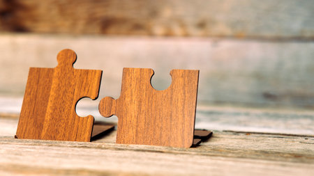 Brown pieces of puzzle stand on wooden table. Empty copy space for inscription or objects. idea,...