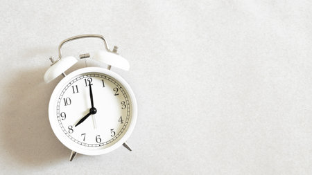 White alarm clock set at eight o'clock isolated on white background.