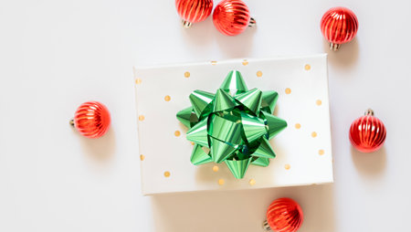 Christmas Eve concept. Top view photo of gift boxes with ribbon bows green red baubles gold star ornaments and pine branches on isolated red background with copyspace in the middleの写真素材
