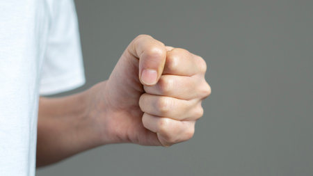 Clenched fist of man's hand isolated on a gray background. Asian man's hand skin tone.の写真素材