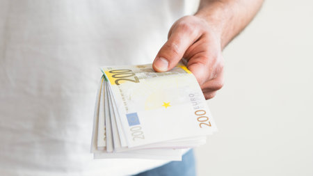 A man hand offering euro notes and holding bunch of euro money. Euro, dollar banknotes, European...