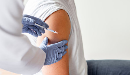 Vaccine or flu shot in injection needle. Doctor working with patient's arm.の写真素材