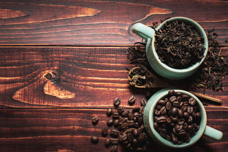Arabica coffee beans and chinese tea  leaves on the wooden background.Two popular natural food productsの写真素材