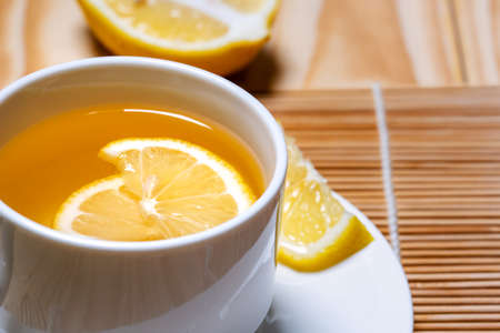 Fresh honey mixed with fresh lemon juice  and hot water in white cup for drink .Lemon slices in a cup and plate, healty food close-upの写真素材