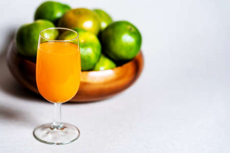 Fresh orange juice in a glass and have background are oranges  in wooden bowl ,asia fruits,has copy space for wordingの写真素材