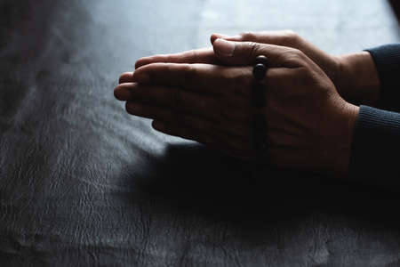 A man praying hands pay respect to sacred things.He has faith in God.Wooden rosary in handの写真素材