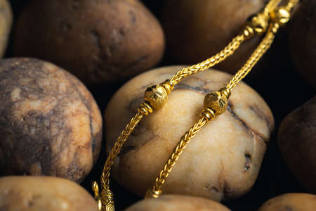 Close-up gold necklace jewelry on river gravel background.Vintage necklace,ancient jewelry,used for vintage backgroundの写真素材