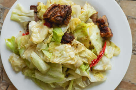 Stir fried collard greens with fried pork in the plate for breakfast or lunch or dinner,The food are collard greens with fried pork ,chili and garlic mixed together by heat.some menu on food tableの写真素材
