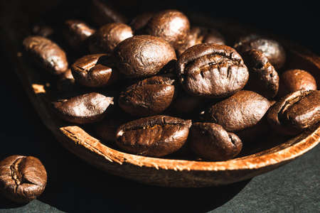 Close-up coffee beans in wooden spoon on black background.Macroの写真素材