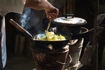 The man cooking vegetables in frying pan on vintage stove ,cooking with firewood ,cook by myself for eat in homeの写真素材