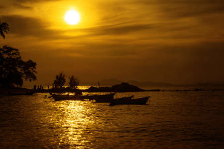 View of fishing boats moored on the seashore in the twilight, backlit photography,golden light,background landscape of the sea in eveningの写真素材