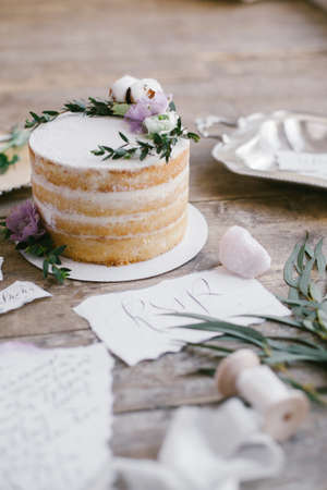 Graphic arts of beautiful wedding calligraphy cards and round cake with floral decorations on wood background.の写真素材
