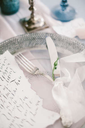 Graphic arts of beautiful wedding calligraphy cards and silver plate with cutlery on festive wedding table.の写真素材