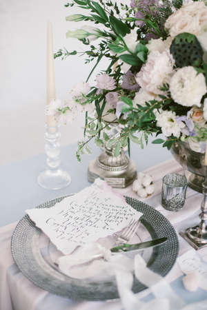 Graphic arts of beautiful wedding calligraphy cards and silver plate with cutlery on festive wedding table.の写真素材