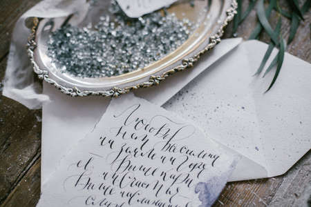 Graphic arts of beautiful wedding calligraphy cards and silver plate with silk ribbon on wood background.の写真素材