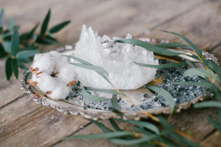 Silver plate with two wedding ring and white crystal on wood background.の写真素材