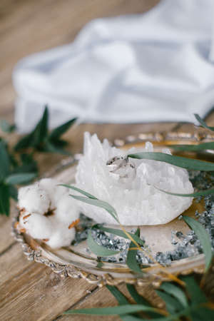 Silver plate with two wedding ring and white crystal on wood background.の写真素材