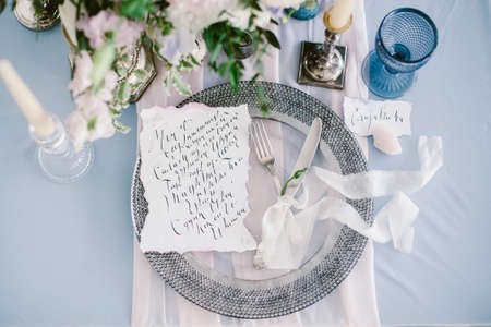Graphic arts of beautiful wedding calligraphy cards and silver plate with cutlery on festive wedding table.の写真素材