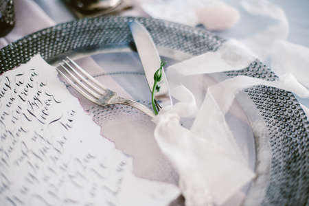 Graphic arts of beautiful wedding calligraphy cards and silver plate with cutlery on festive wedding table.の写真素材