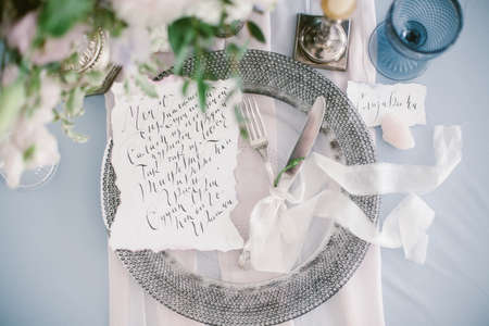 Graphic arts of beautiful wedding calligraphy cards and silver plate with cutlery on festive wedding table.の写真素材